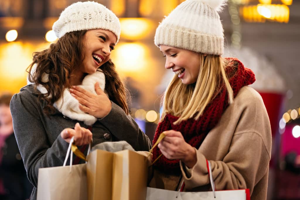 Happy friends are shopping for presents at Christmas. People xmas holiday sale shopping concept